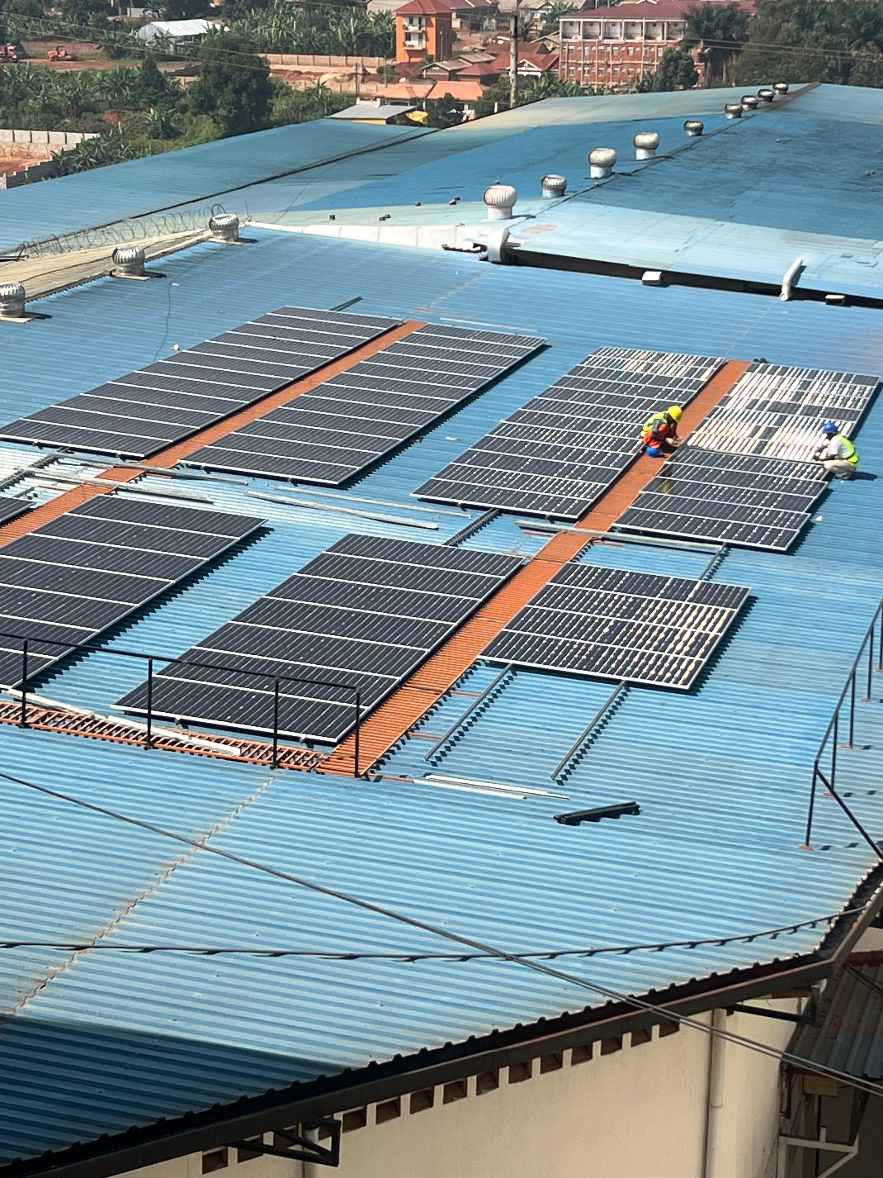 Solar panel installation on a large industrial rooftop with workers